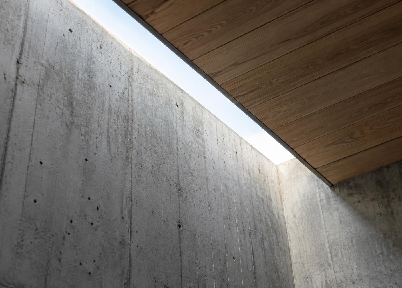 Detalhe arquitetônico entre parede de concreto e forro de madeira
